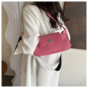 Detailed view of pink pebble leather shoulder bag with silver clasp on white coat