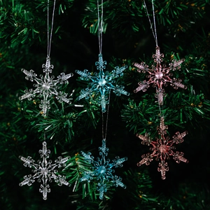 Décorations de Noël en acrylique rose, bleu et blanc suspendues à un sapin vert