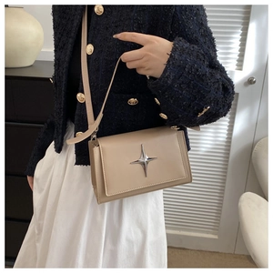 Dettaglio borsa a tracolla beige in pelle con fibbia a stella e giacca in tweed