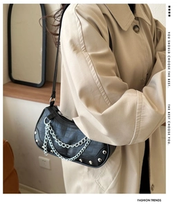 Side view of black embossed leather half-moon bag with silver chain and stud details
