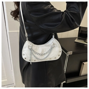 Detail of white half-moon crossbody bag with crocodile pattern and silver chain accents