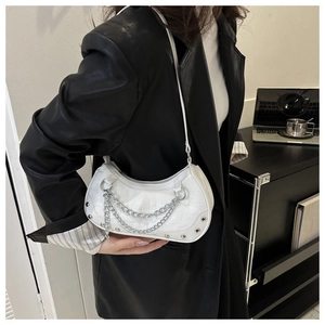 Detail of white crocodile texture crescent bag with silver chains worn on black leather blazer