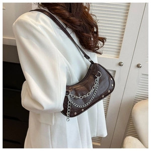 Detailed view of brown crocodile texture underarm bag with silver chain and rivets