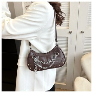 Detail of dark brown crocodile-embossed underarm bag with silver metal chain decor
