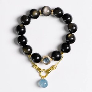Armband aus goldenem Obsidian mit Aquamarin-Perle und Metallanhänger auf Weiß