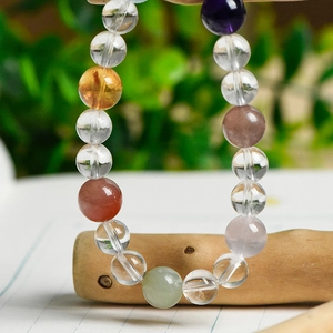Natural 8mm white crystal bracelet with multi-gemstone beads on a wooden stand