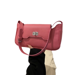 Pink lychee texture shoulder bag with silver turn-lock clasp shown in hand