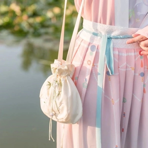Close-up of bamboo embroidery on an off-white silk drawstring bag with elegant tassels