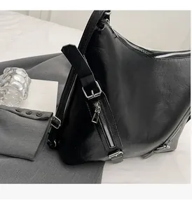 Detail of glossy black leather handbag with premium silver hardware on textured fabric