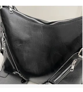 Detail of soft black leather texture and silver zipper hardware on the shoulder bag