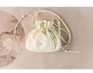 Detail of embroidered white deer and green bamboo leaves on cream canvas drawstring bag