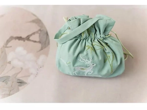 Detail of mint green lace drawstring bag with embroidered white deer and bamboo