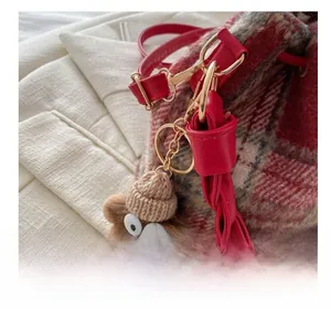 Detail of cute bear plush charm with knit hat on plaid wool bucket bag with gold metal clasp