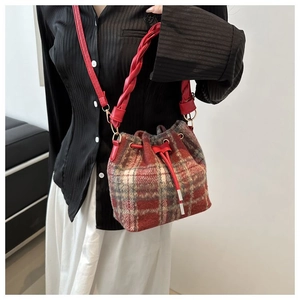Detailed view of red plaid tweed bucket bag with woven handle and drawstring closure