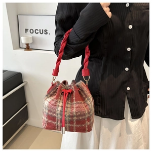 Detail of red-brown plaid wool bucket bag with twisted rope handle and drawstring closure