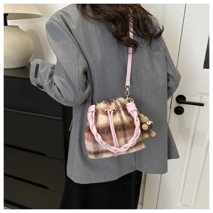 Detail of pink plaid plush bucket bag with woven leather handle and cartoon pendant