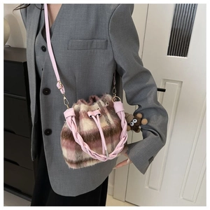 Detail of plaid wool bucket bag with pink woven handle and cute monkey charm decoration