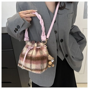 Close-up of pink plaid faux fur bucket bag with drawstring and cute bear charm