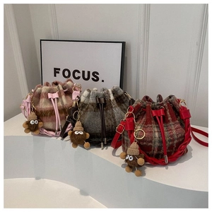 Three colors of plaid wool bucket bags featuring drawstring closures and plush charms