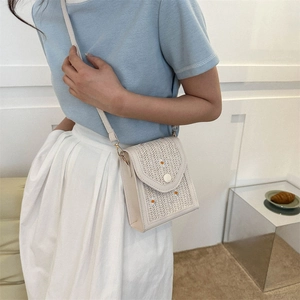 Close-up of woven crossbody bag featuring daisy embroidery and gold hardware details