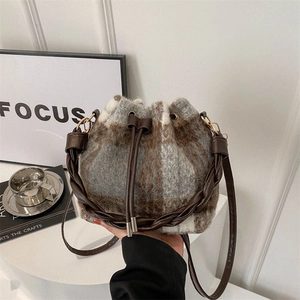 Brown plaid wool bucket bag with drawstring closure and woven leather handle for winter