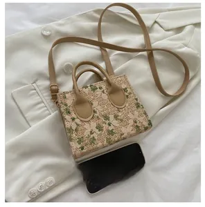 Mini woven crossbody bag with floral lace embroidery and leather handles on a blazer
