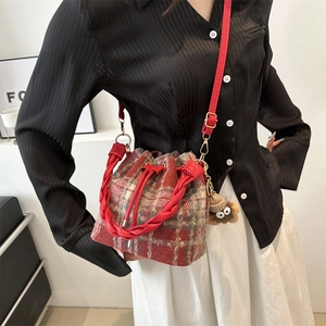 Red plaid wool bucket bag with monster charm shown as a stylish crossbody handbag