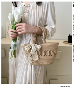 Close-up of beige hand-woven straw bag with ripple texture and lace ribbon detail