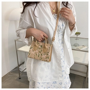 Detail of woven lace mini bag with delicate floral embroidery and leather handle