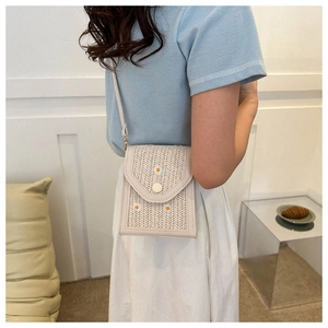 Detailed view of woven crossbody bag with white daisy embroidery and gold hardware