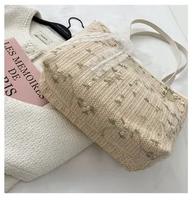 Close-up of floral embroidery and white lace trim on a beige straw tote bag