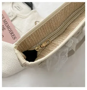 Detail of a straw tote bag with top zipper closure and elegant lace trim edges