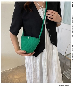 Gros plan du sac seau tressé vert avec un fermoir en perle et une bandoulière fine