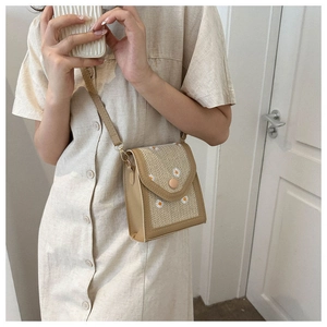 Detail of woven straw crossbody bag with white daisy embroidery and wavy edge design