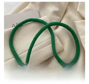 Détail de la bandoulière tressée vert foncé épaisse posée sur un tissu beige élégant