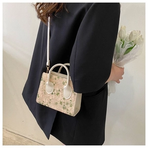 Mini woven crossbody bag with green floral lace detail shown on a model's shoulder
