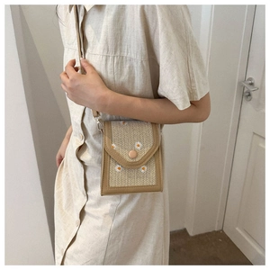 Close-up of woven crossbody bag with daisy embroidery and khaki leather trim detail