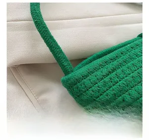 Coutures détaillées sur sac seau tressé vert montrant la bandoulière et le savoir-faire