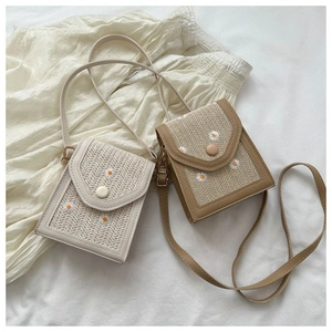 Close-up of woven mini crossbody bags with daisy embroidery in white and khaki