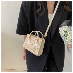 Mini floral woven tote bag with cream handles shown in a lifestyle street style shot