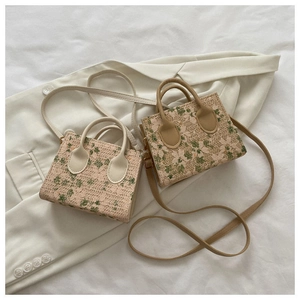 Close-up of mini woven floral lace handbags in beige and tan on a white blazer