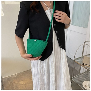 Détail du sac seau en maille verte avec bouton perle blanche porté par un mannequin