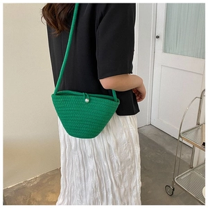 Détail du sac seau tressé vert avec fermoir perle et motif tricoté texturé à la main