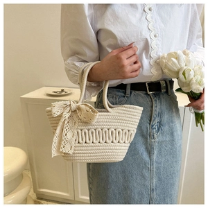 Detail of cream woven tote bag with delicate white lace bow and ripple texture