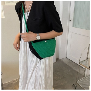 Détail du sac seau tressé vert avec fermoir perle et bandoulière élégante
