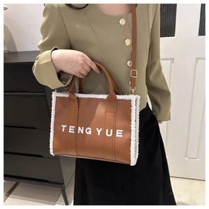 Détail du sac cabas en cuir marron avec bordure en peau de mouton blanche et logo TENG YUE