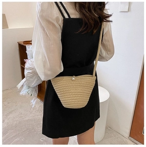 Détail du sac seau en paille tressée avec texture ondulée et perle sur un mannequin