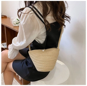 Détail d'un sac seau tressé beige avec fermoir perle et bandoulière élégante