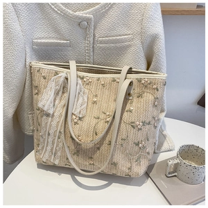 Close-up of woven straw tote bag featuring delicate floral embroidery and lace bow detail