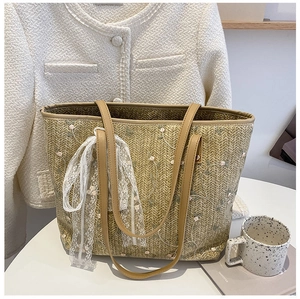 Detail of straw tote bag with floral embroidery, lace bow and brown leather straps